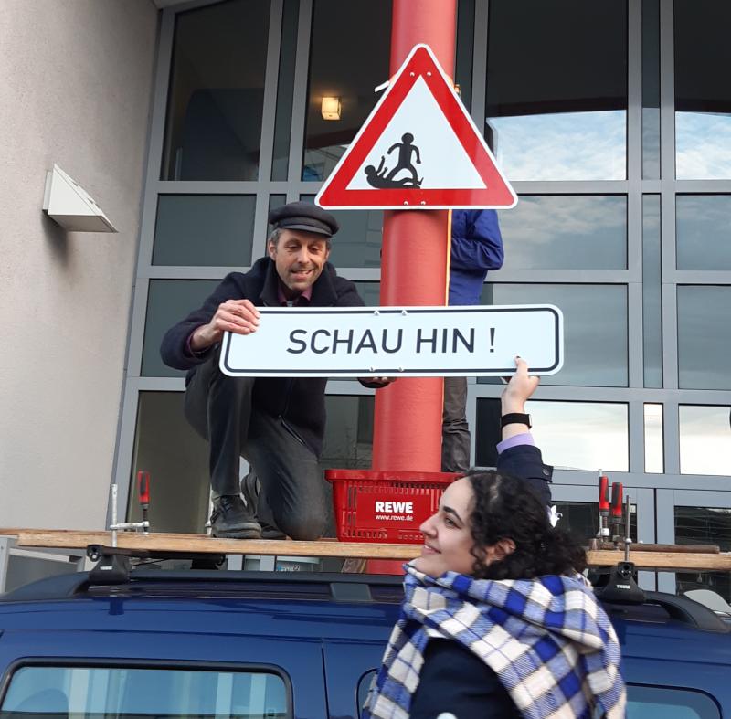 Künster Johannes Volkmann mit Studentin beim Anbringen eines der Verkehrsschilder der Gerechtigkeit