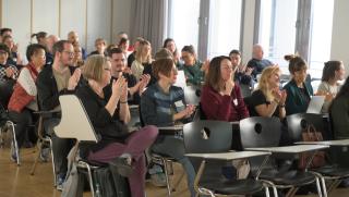 applaudierende Teilnehmende im Hörsaal